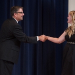 Doctor Smart shaking hands with an award recipeint in a black dress